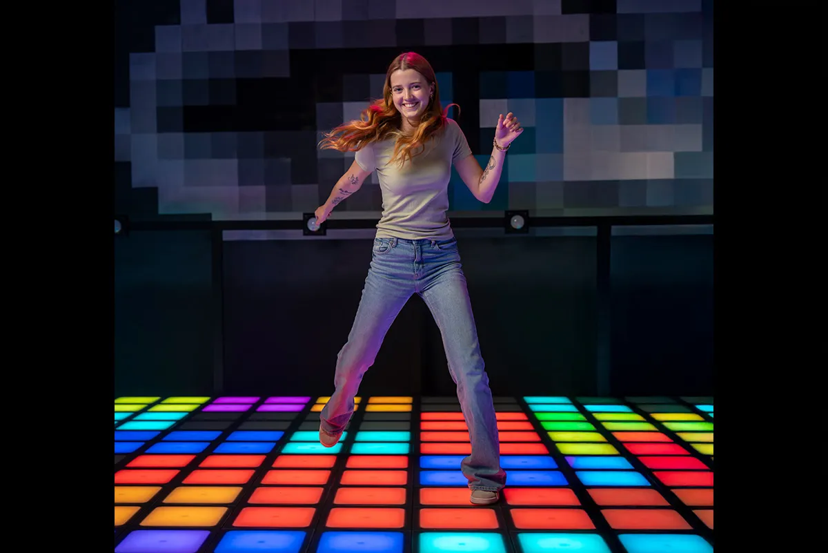 zwei junge maedchen springen ueber die bunten felder des pixelgames fussboden